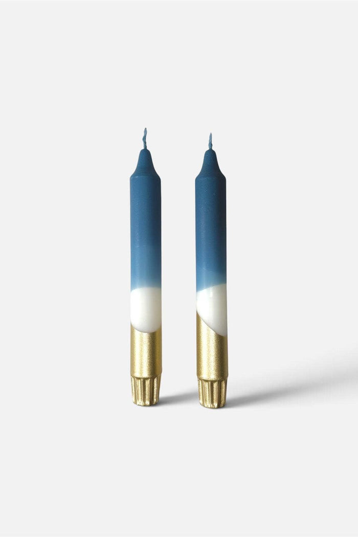 Two taper candles with a blue-to-white gradient upper body, white lower section, and metallic gold base, shown on a light gray background.