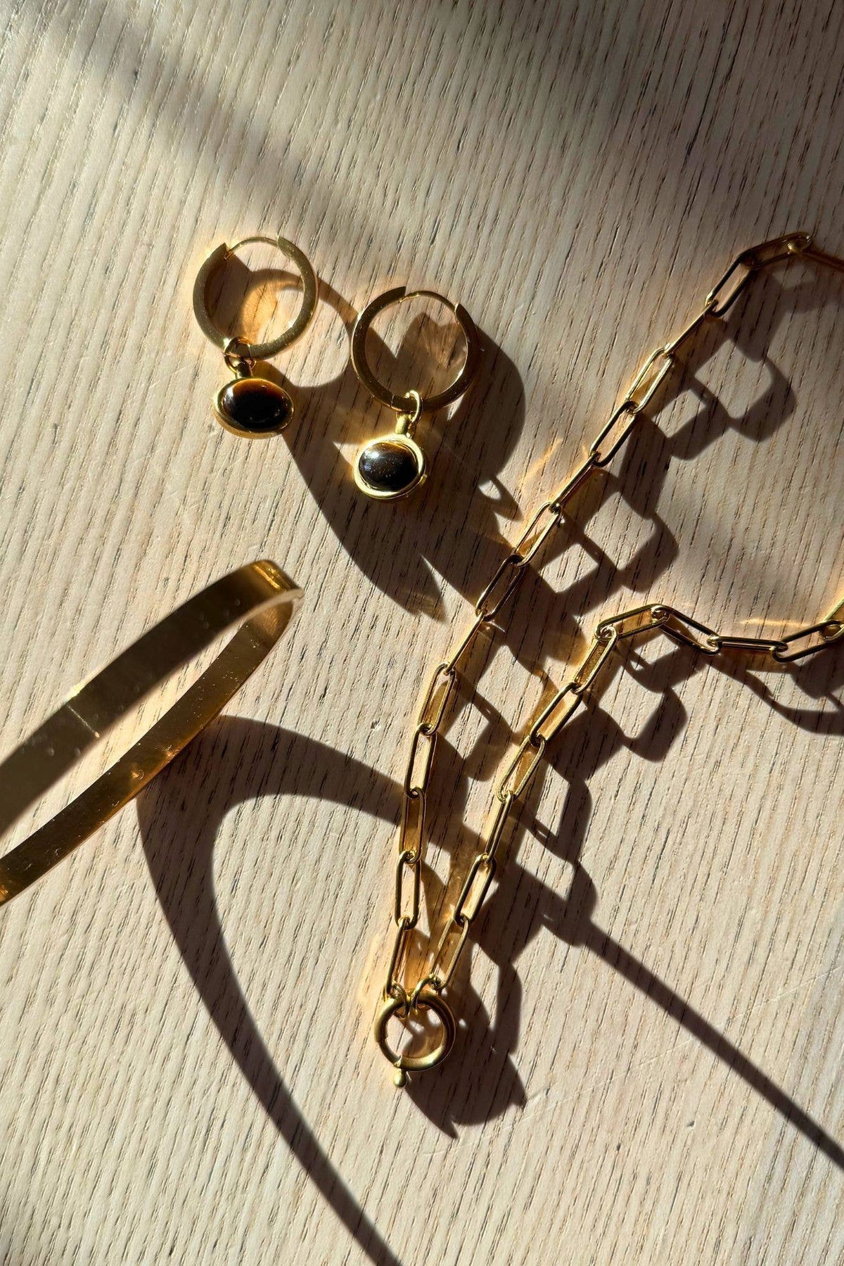Gold bracelet and earrings on a wooden surface