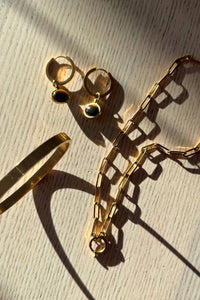 Gold bracelet and earrings on a wooden surface
