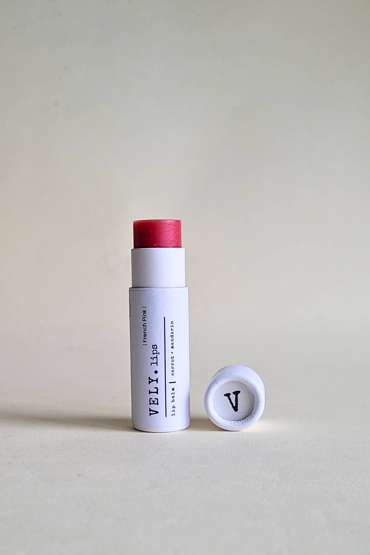 White cylindrical product with red cap and visible branding on a beige background