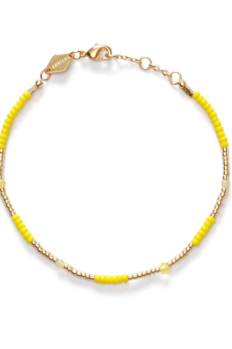 Gold bracelet with yellow beads on a white background