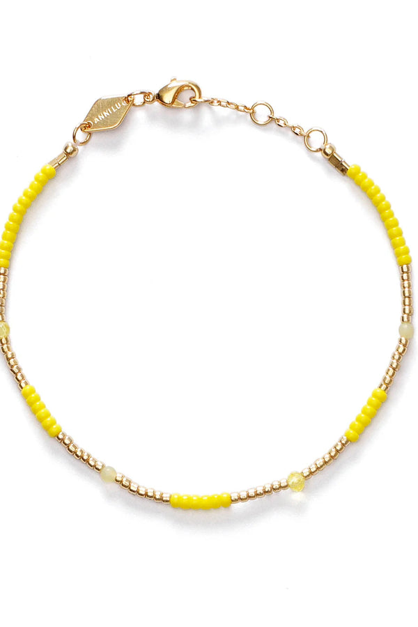 Gold bracelet with yellow beads on a white background