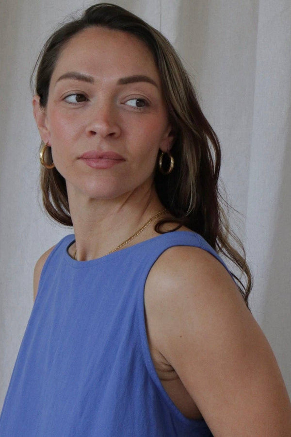 Woman wearing a blue sleeveless top against a plain background