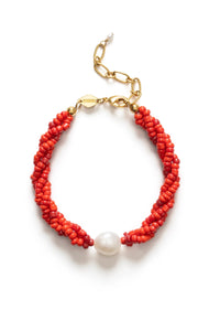 Red beaded bracelet with a pearl accent on a white background