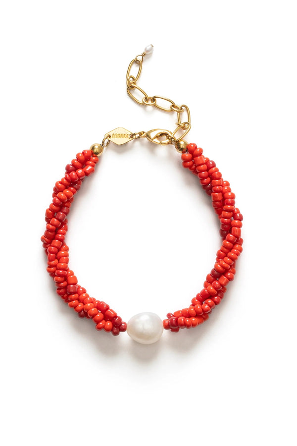 Red beaded bracelet with a pearl accent on a white background