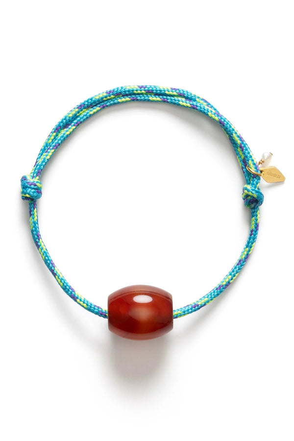Bracelet with blue and green pattern and red bead on a white background