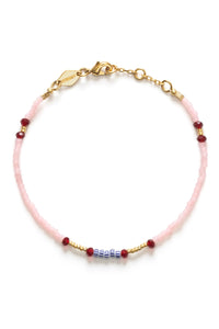 Pink beaded bracelet with gold accents on a white background