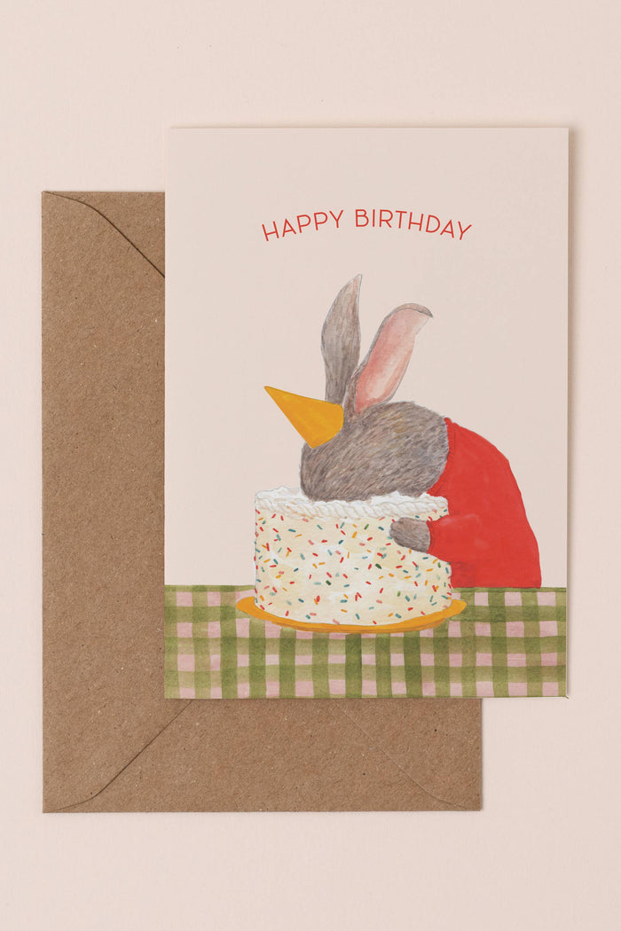 Birthday card with a rabbit character and cake illustration on a beige background