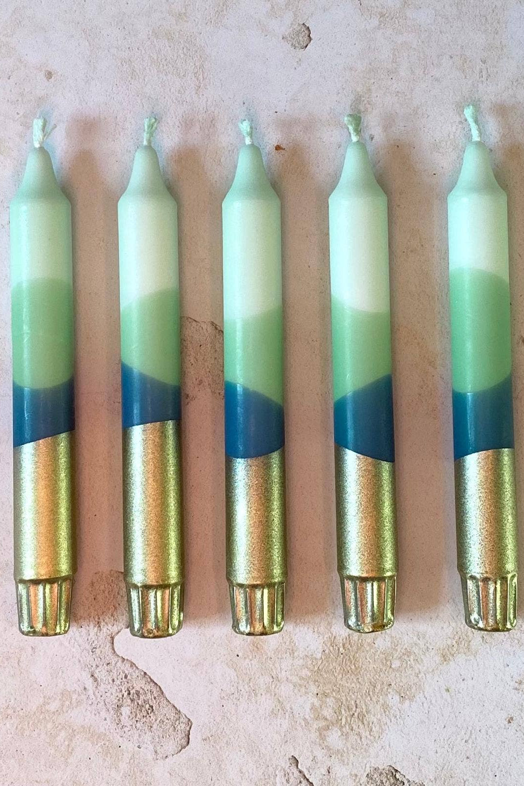 Five candles with gradient colors on a textured surface