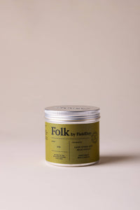 Green jar with silver lid labeled 'Folk' on a beige background