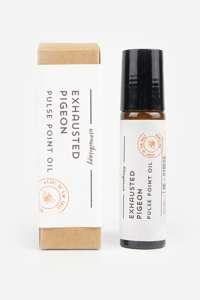 A bottle of Exhausted Pigeon Pulse Point Oil next to its kraft paper packaging box, displayed on a clean white background.