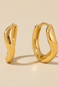 Gold hoop earrings on a beige background