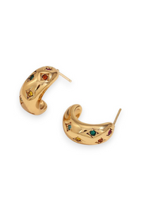 A pair of gold crescent-shaped hoop earrings decorated with small, colorful gemstones in red, green, and yellow, shown on a plain white background.