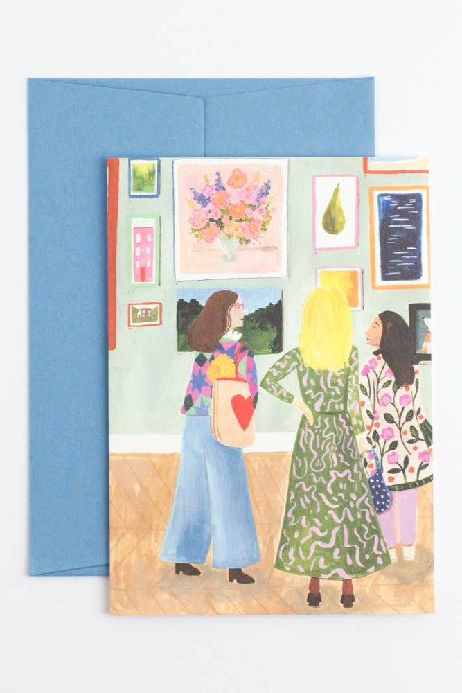 Greeting card with illustration of three women in a gallery setting, featuring a blue envelope.