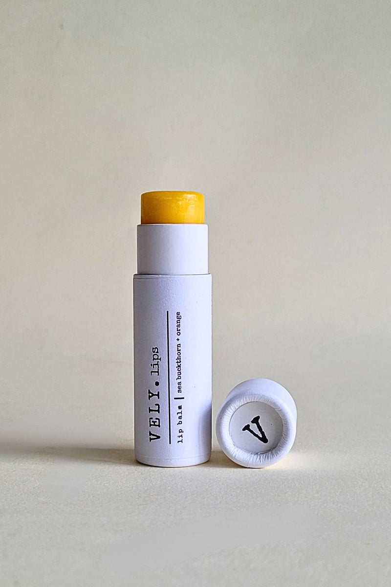White lip balm stick with yellow cap and visible branding on a light gray background