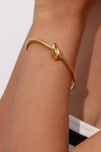 Gold bracelet on a person's wrist with a neutral background