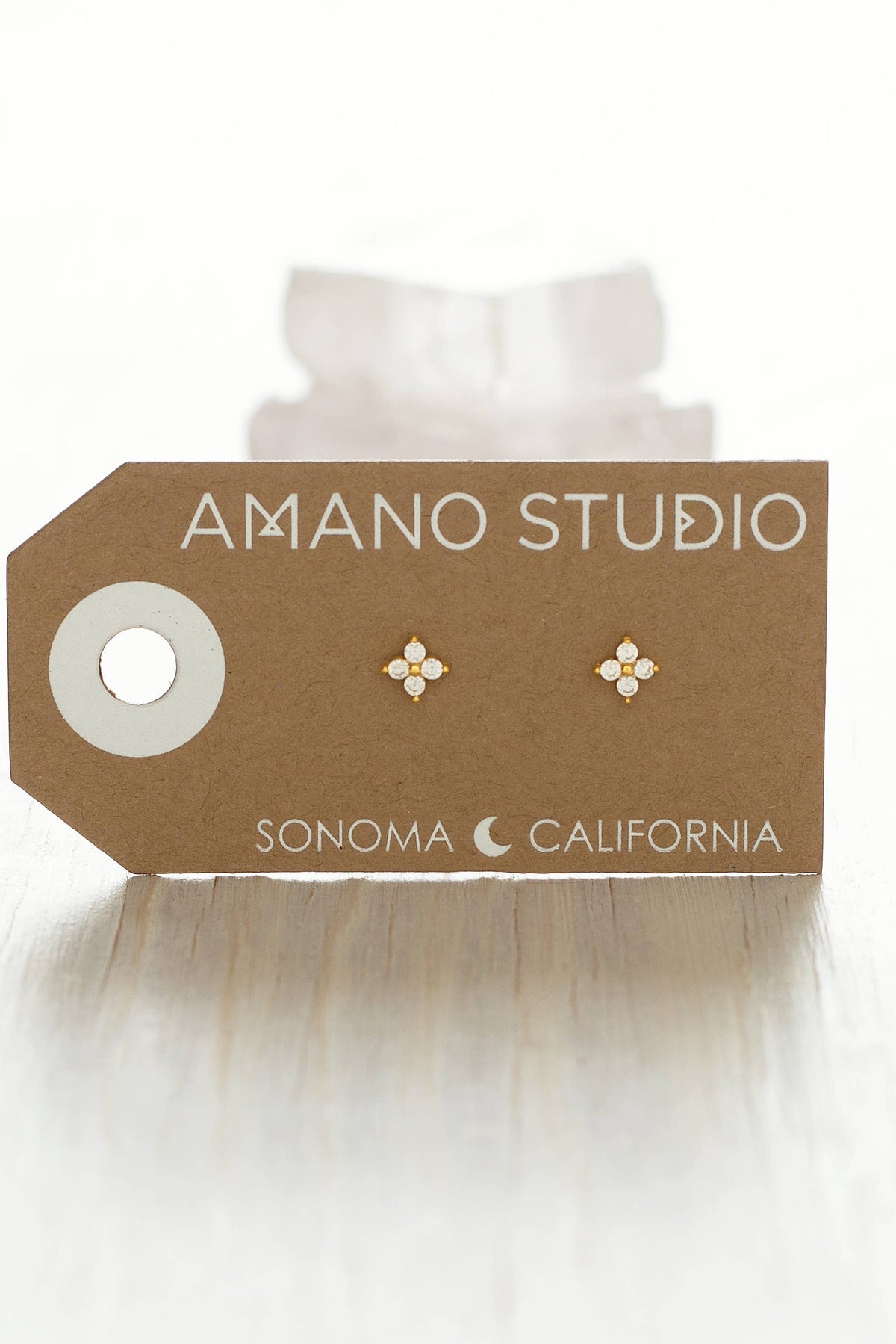 Earring card with earrings on a white background, featuring 'AMANO STUDIO' branding.