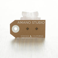 Earring card with earrings on a white background, featuring 'Amano Studio' branding.