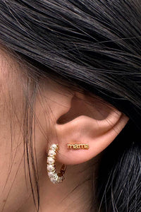 Close-up of an ear wearing gold hoop earrings with a blurred background
