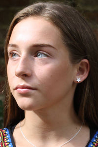 Close-up of a person wearing a colorful patterned top with a necklace and star-shaped earrings.