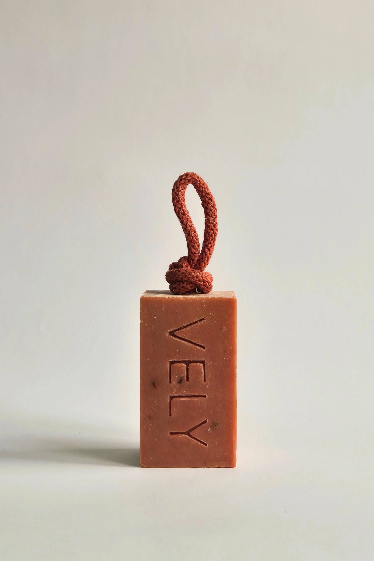 Bar of soap with a rope handle on a light background, branded 'VELY'.