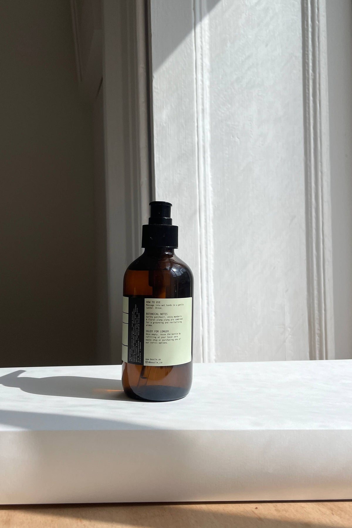 Brown bottle with a label on a white surface near a window