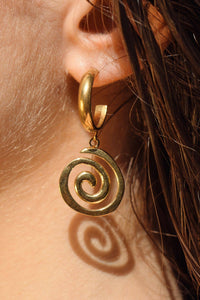 Gold spiral earring worn by a person with brown hair.