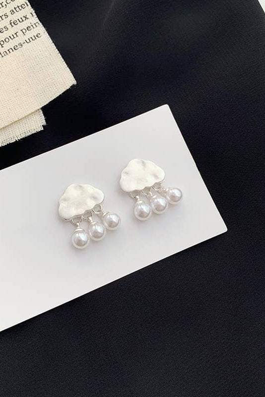 Pearl earrings on a white card with a black background