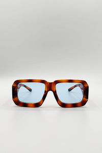 Sunglasses with tortoiseshell frame and blue lenses on a light gray background