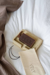 Bar of soap in a wooden box with 'VELY' branding on a white surface.