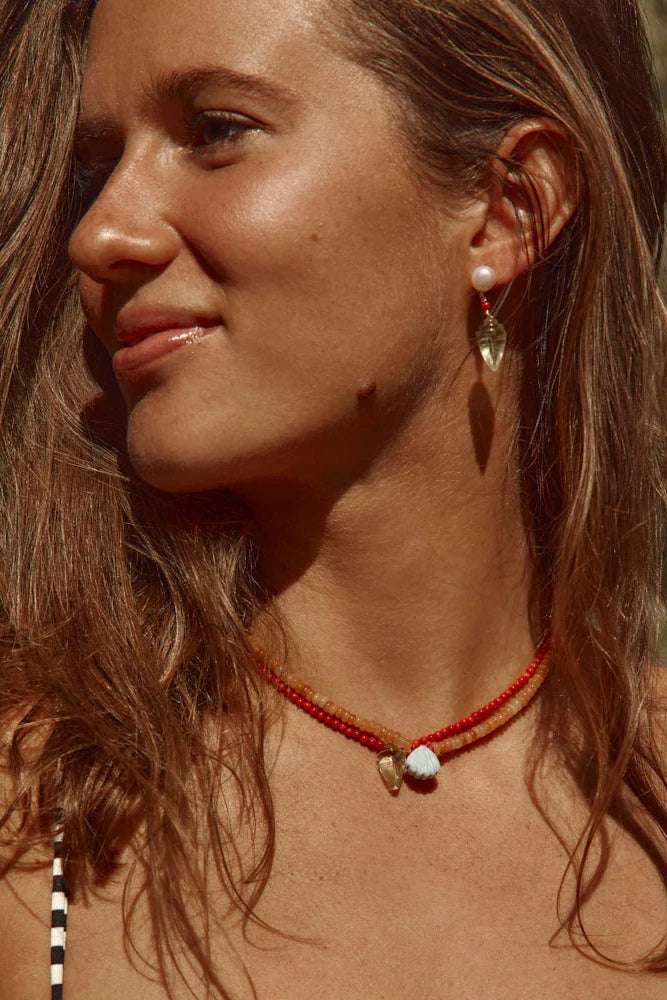 Woman wearing a red necklace and earrings outdoors