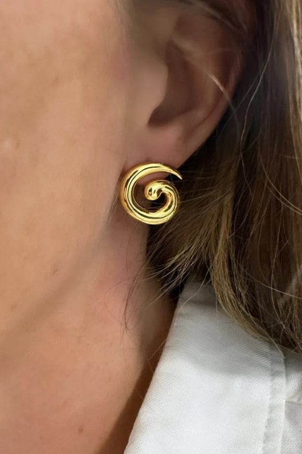 Close-up of a person wearing a gold spiral earring.