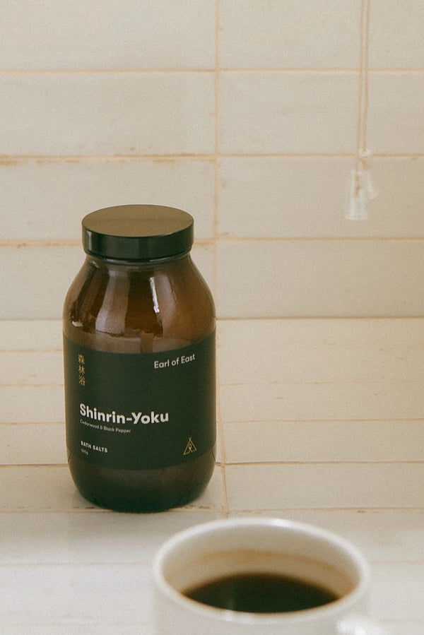 Brown bottle labeled 'Shinrin-Yoku' on a tiled surface with a cup of coffee.