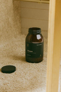 Brown bottle labeled 'Onsen' on a beige towel with a blurred background