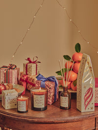 Candles, gift boxes, and decorative items on a wooden table with a warm ambiance.