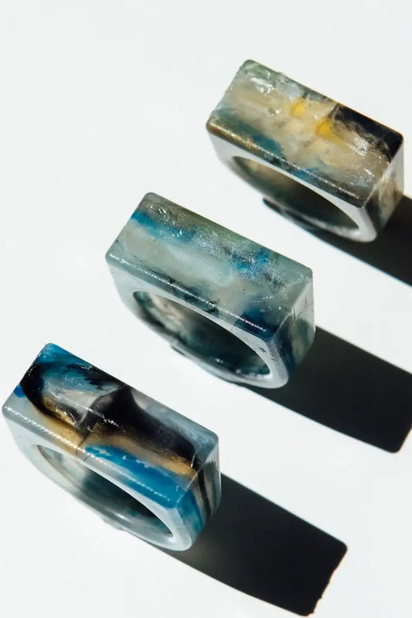 Three resin rings with abstract designs on a white background