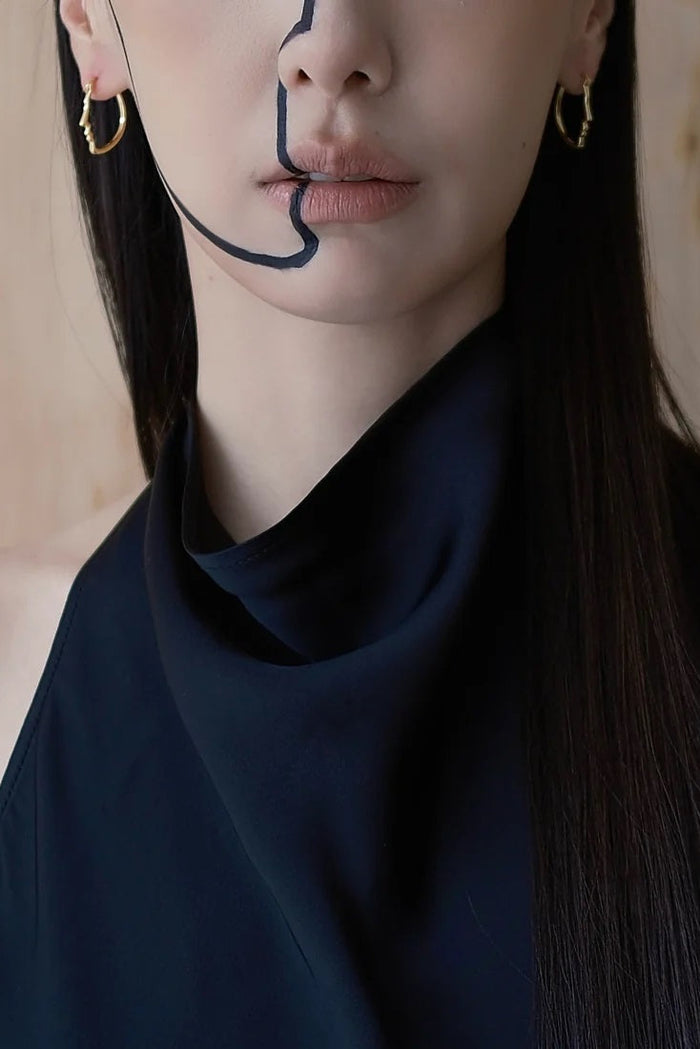 Woman wearing a black top with minimal makeup against a neutral background