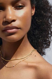 Close-up of a woman wearing a gold necklace with a blurred background