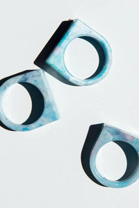 Three geometric earrings with a blue and black marbled pattern on a light gray background