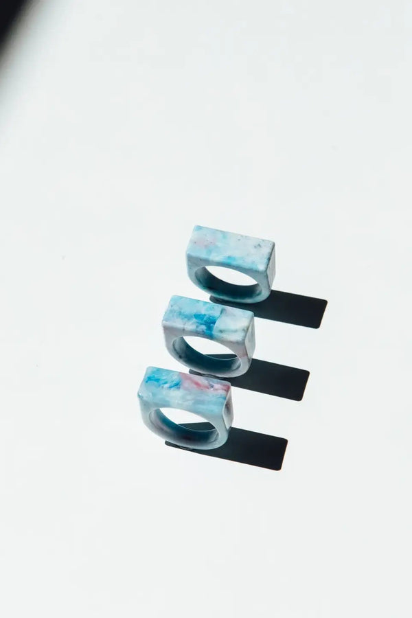 Set of three blue and white marbled rings on a light gray background