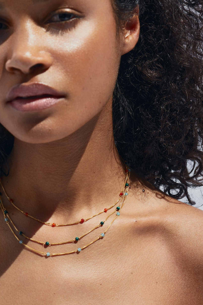 Close-up of a woman wearing a layered necklace with a blurred background