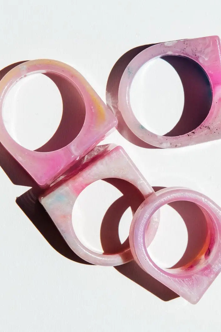 Four pink and brown rings stacked on a light gray background