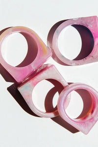 Four pink and brown rings stacked on a light gray background