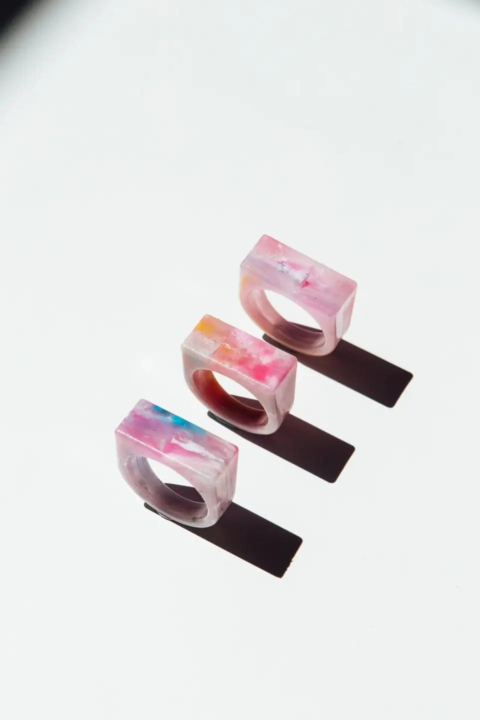 Three colorful resin rings on a white background