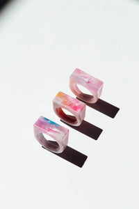 Three colorful resin rings on a white background