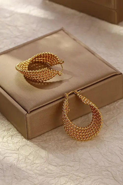 Gold hoop earrings on a beige jewelry box with a textured surface background