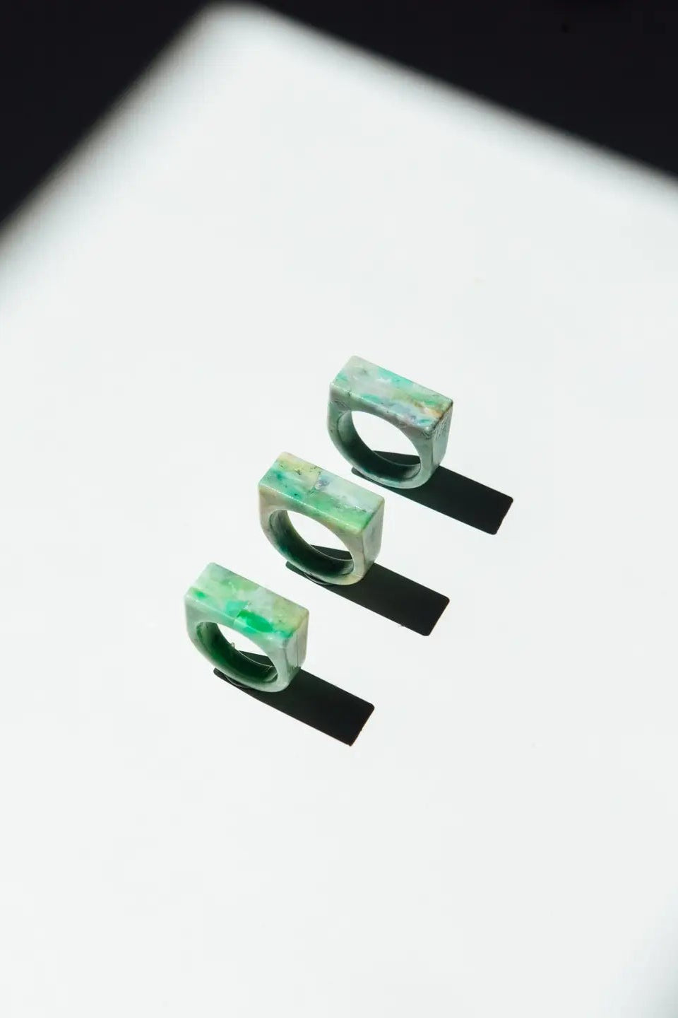 Three green rings on a reflective surface with a dark background