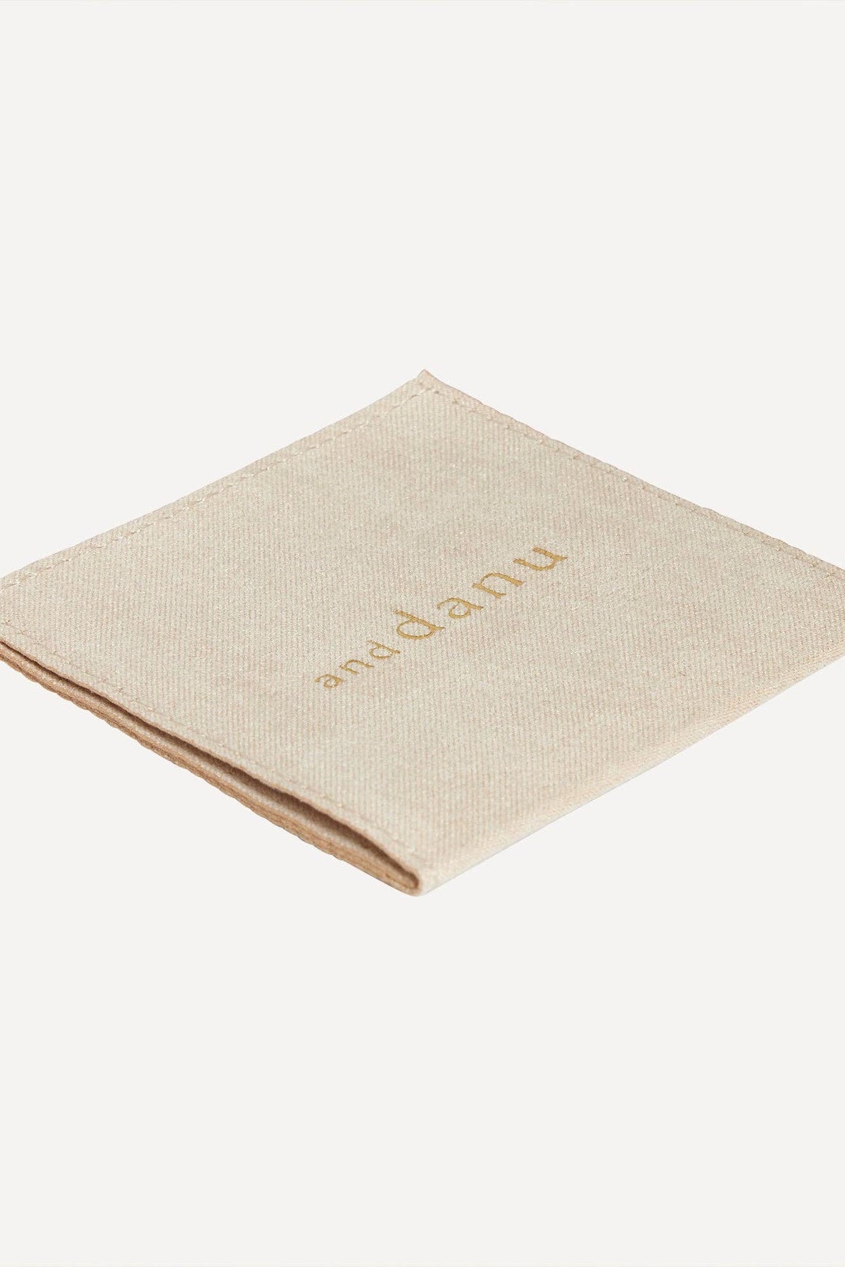 Beige napkin with 'an-danu' branding on a white background