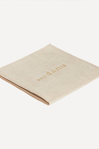 Beige napkin with 'an-danu' branding on a white background