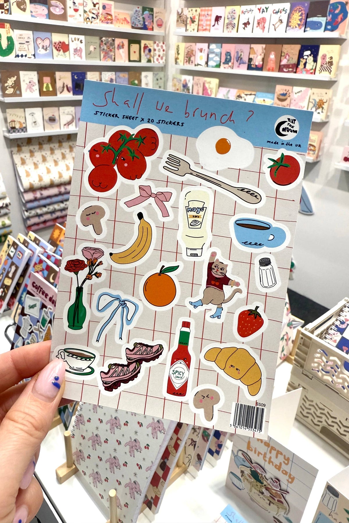 Sheet of stickers with various illustrations held in front of a store shelf.